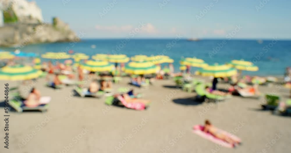 A group of various people spending time on the beach to catch a tan. A blurred group of people relaxing on the beach A group of various people spending time on the beach to catch a tan. A blurred group of people relaxing on the beach