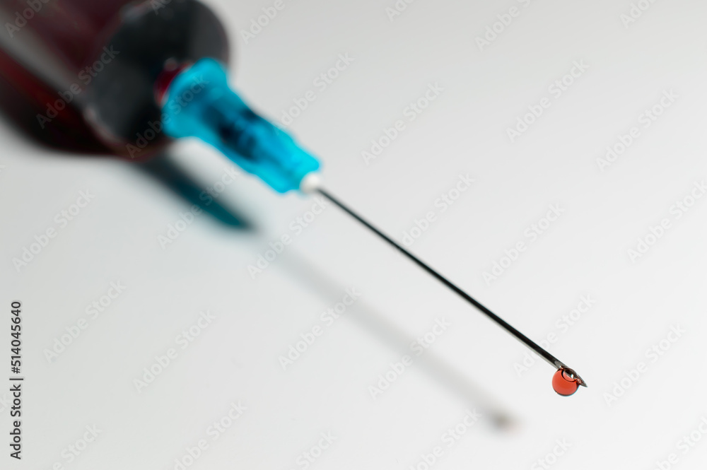 Medical syringe with blood dripping from the end of the needle. Blood test against corona virus and monkeypox. Medical treatment. Medical syringe with blood dripping from the end of the needle. Blood test against corona virus and monkeypox. Medical treatment.