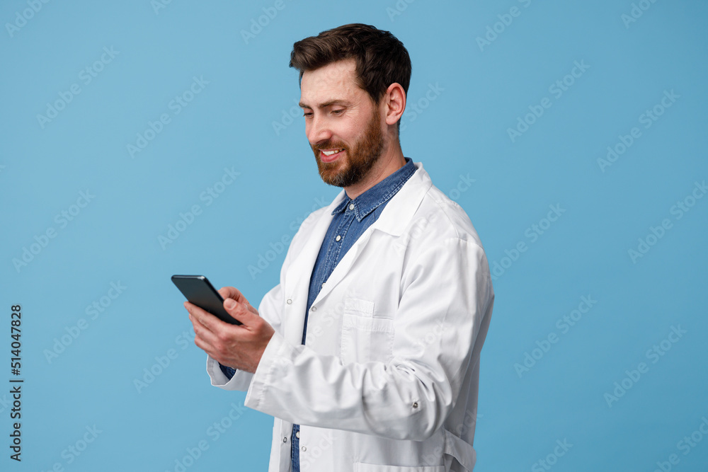 Smiling medical specialist using mobile phone over blue studio background