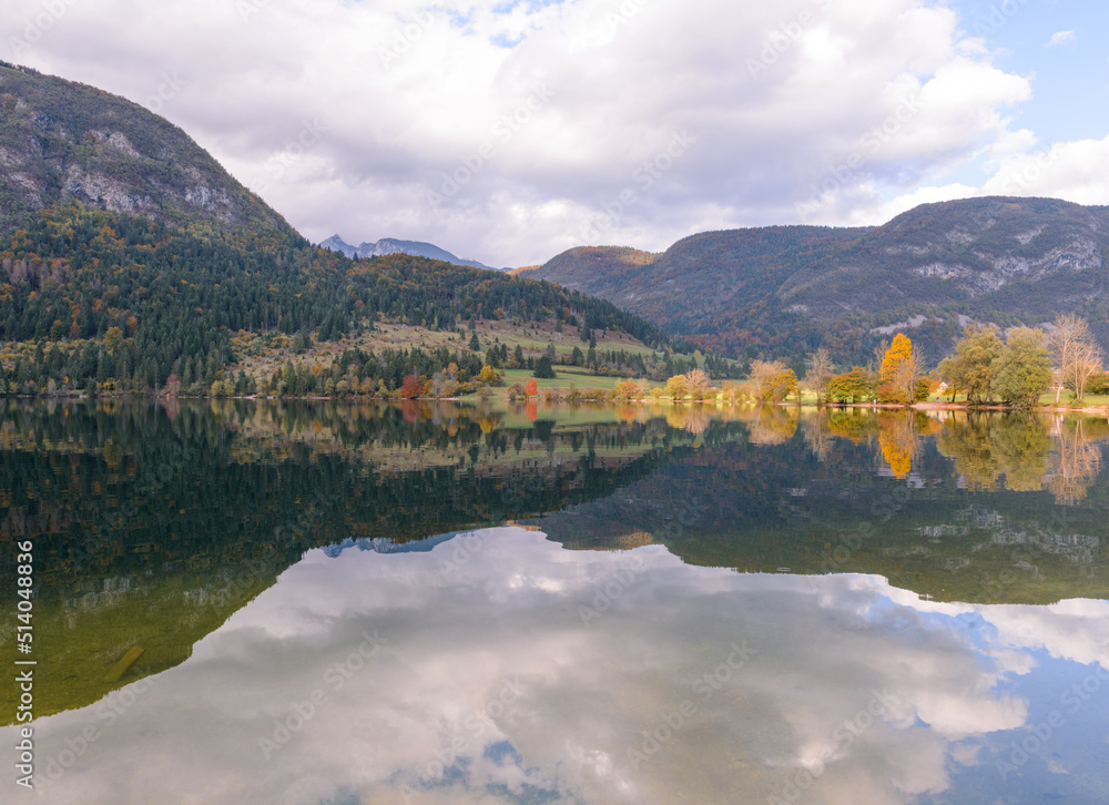Autumn landscape by the lake Bohinj in Julian Alps. Fascinating reflectins in the lake on a cloudy day.