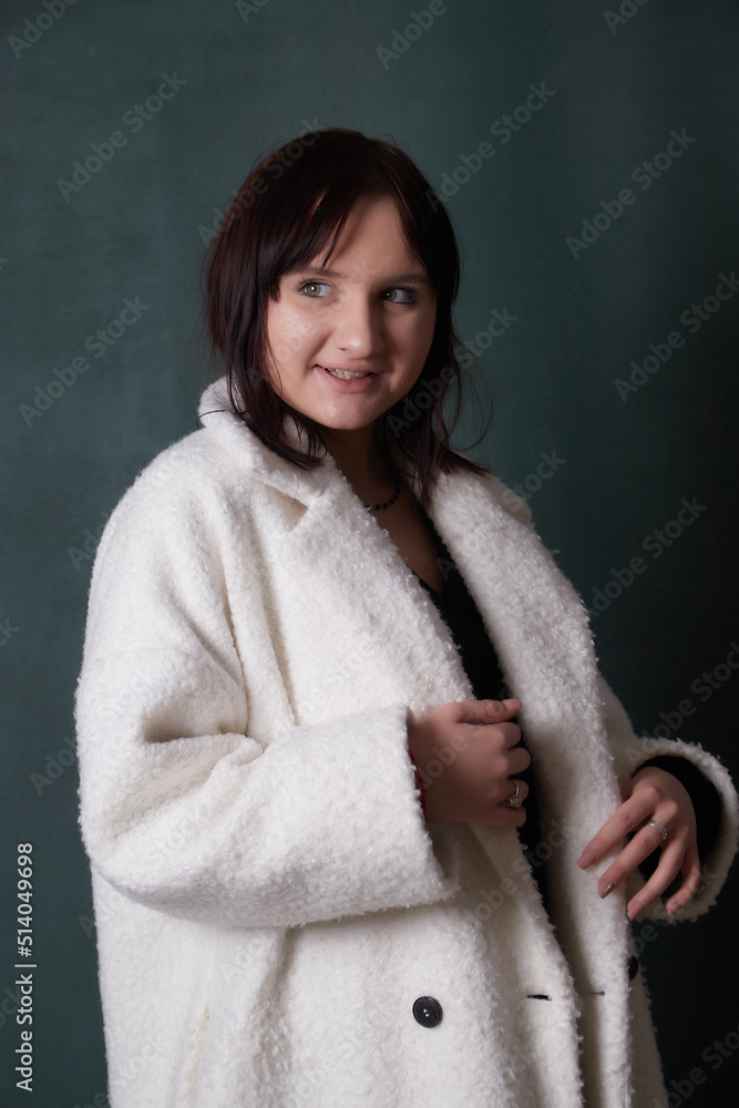 Young elegant woman in trendy white coat. Brunette hair, black dress. Fashion autumn or autumn lookbook. Model woman posing in studio Young elegant woman in trendy white coat. Brunette hair, black dress. Fashion autumn or autumn lookbook. Model woman posing in studio