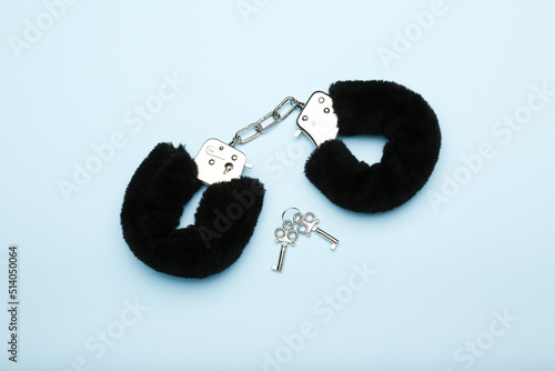 black fluffy handcuffs for adults on a blue background. sex toy