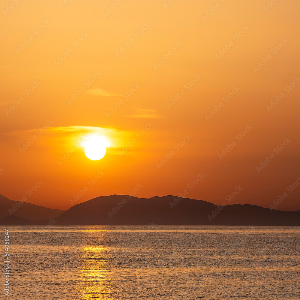 Sea beach and colorful sunset sky. Panoramic beach landscape. Tropical beach and seascape and a distant island in the background. Orange and golden sunset sky, calmness, tranquil sunlight.