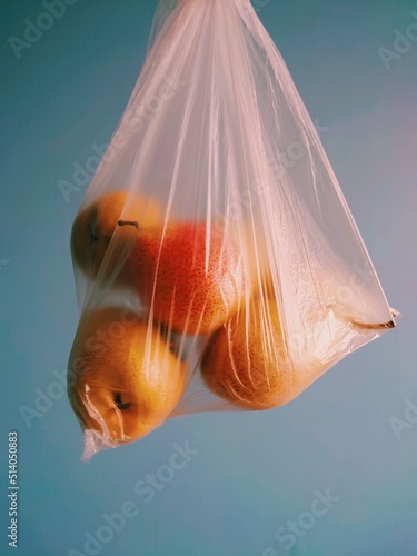 Pears in a closed polythene bag isolated on grey blue background. Ecology. environment, plastic bags, reuse, recycle, zero waste. Vegan, vegetarian food. Healthy lifestyle. Smoothie or pie ingredient photo