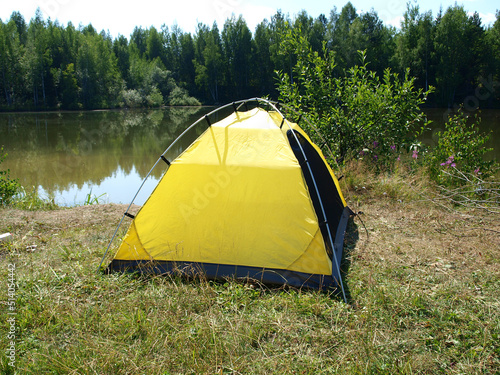 Yellow tourist tent on lake in summer