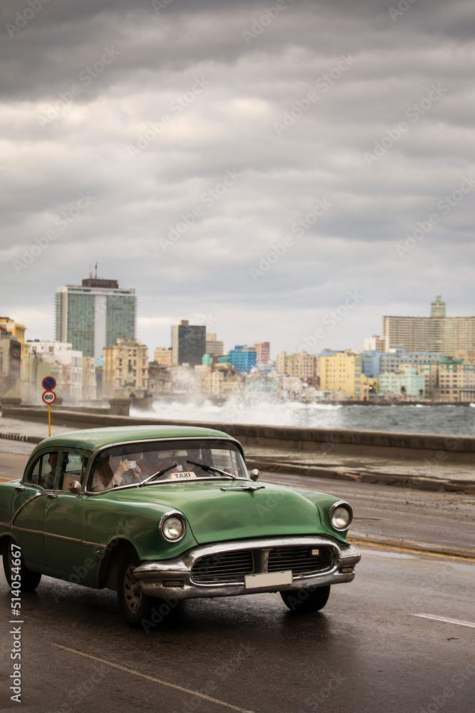 Old car on Malecon street of Havana with storm clouds in background. Cuba