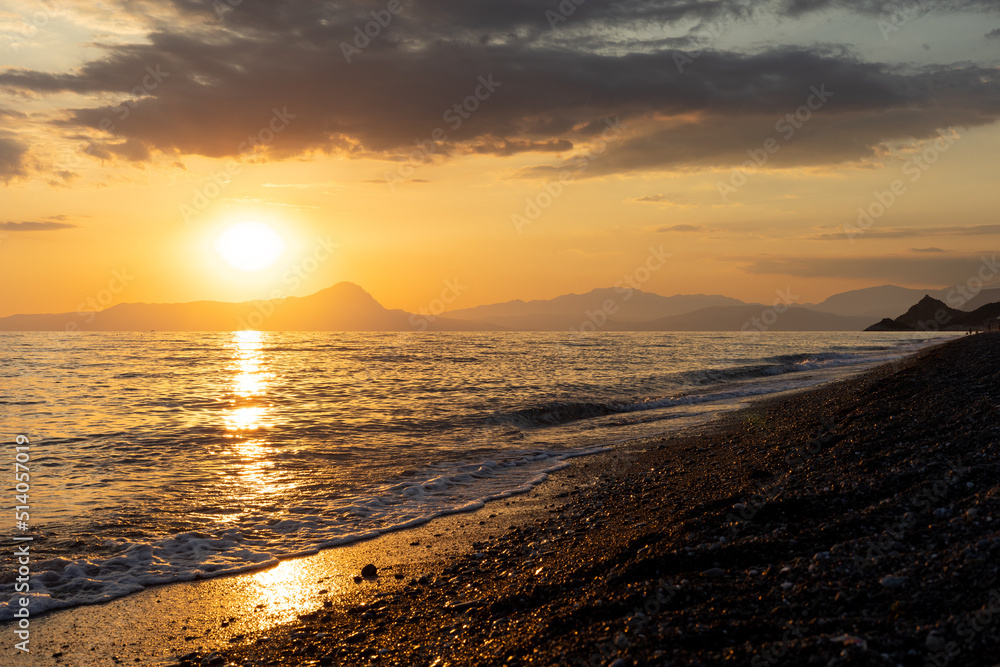 Golden our sunset on mediterranean sea. Clouds over the blue sea and mountains in background