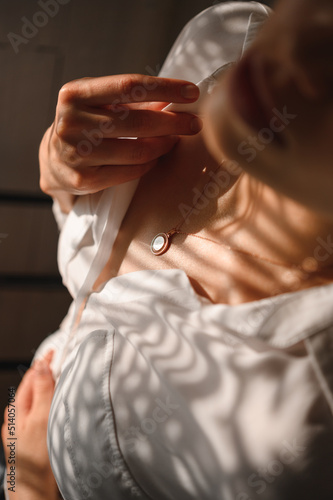 Delicate and sensual blonde in a white silk blouse and with a decoration around her neck