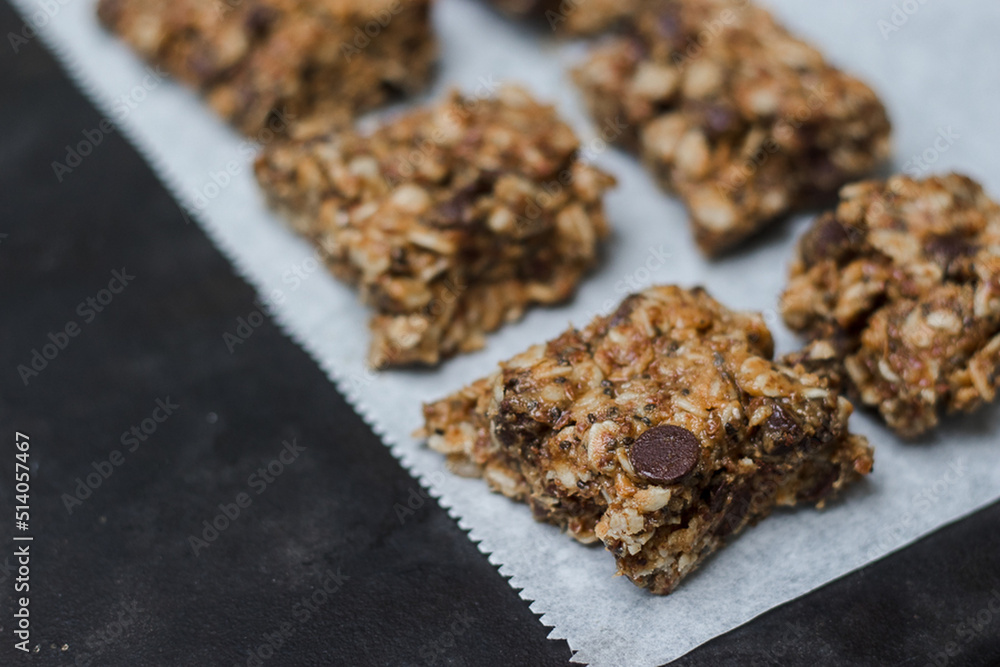 peanut butter chocolate chip granola bars with oats on white parchment paper with neutral background peanut butter chocolate chip granola bars with oats on white parchment paper with neutral background