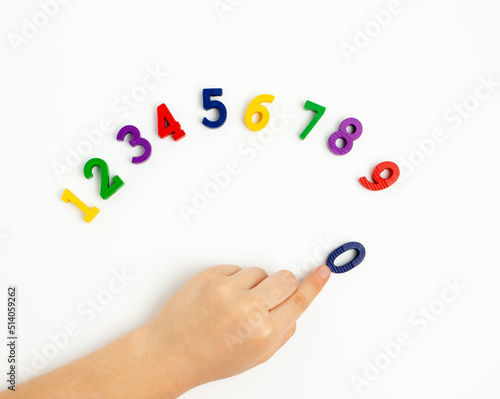 The child uses his index finger to move the number zero up. Early education. We learn colors and count from zero to ten