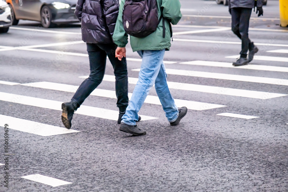 A couple of people cross a pedestrian crossing holding hands. A couple of people cross a pedestrian crossing holding hands.