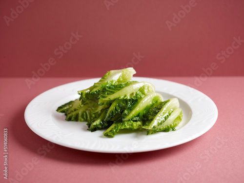 stir-fried local lettuce served in a dish isolated on mat side view on grey background