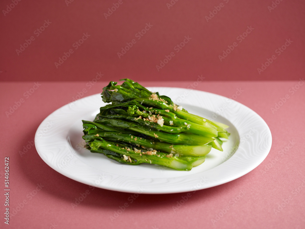 Stir-fried Hong Kong Kai Lan with Garlic with chopsticks served in a dish isolated on mat side view on grey background Stir-fried Hong Kong Kai Lan with Garlic with chopsticks served in a dish isolated on mat side view on grey background