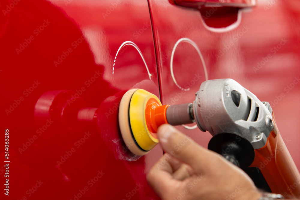 Worker polish a red car. Car detailing - Men using machinery car polishers maintenance to remove marks repair according to the surface of the car's paint Worker polish a red car. Car detailing - Men using machinery car polishers maintenance to remove marks repair according to the surface of the car's paint