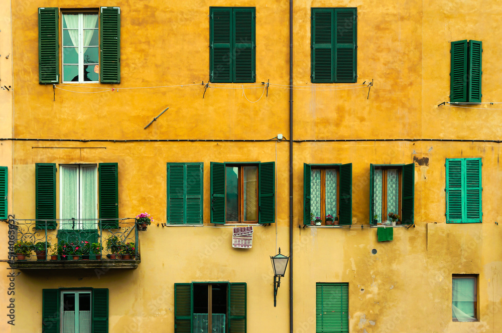 Facades of old buildings in Florence, Italy. Old house near Firenze canal with yellow walls and green blinds.