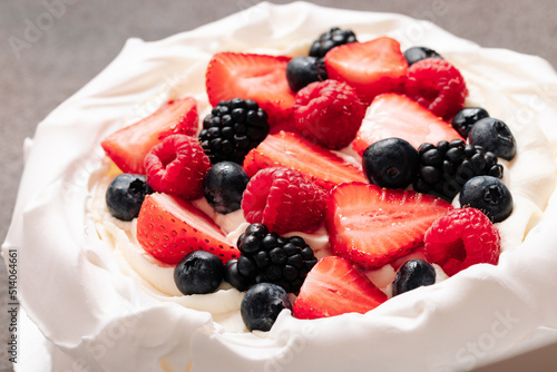 Pavlova meringue cake with fresh berries on brown background