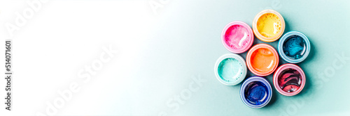 Seven beautiful, bright, mother-of-pearl, multicolored open cans of paint on a bright colored background. The concept of creativity.