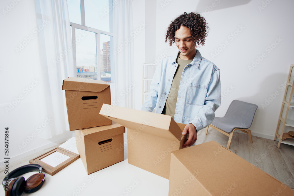handsome guy cardboard boxes in the room unpacking headphones Lifestyle handsome guy cardboard boxes in the room unpacking headphones Lifestyle
