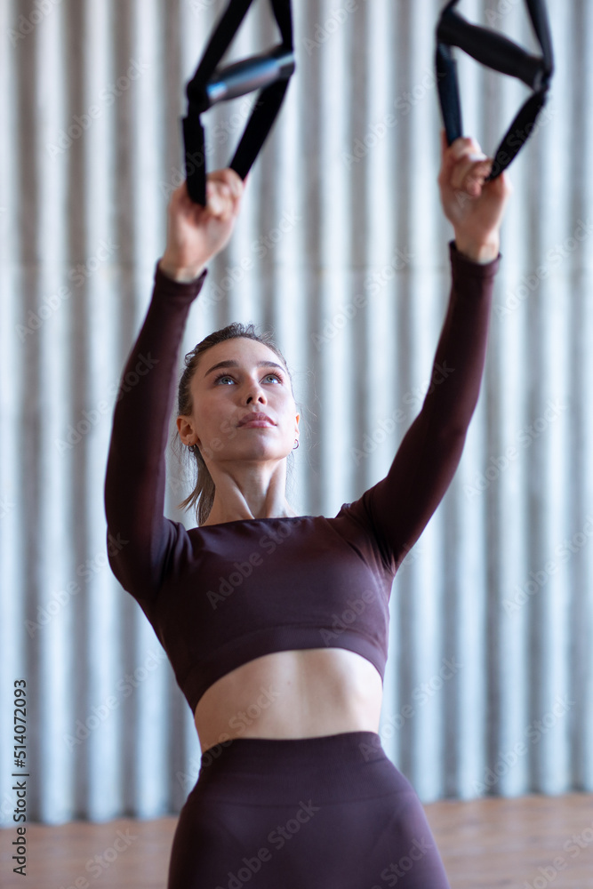 Fototapeta premium Fit woman training with fitness trx straps