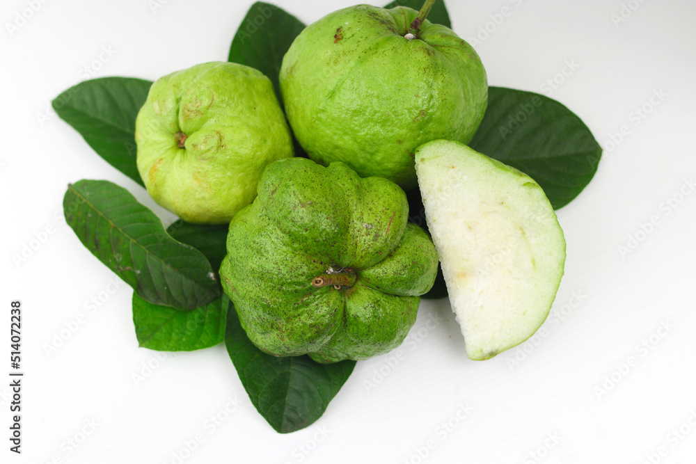 a group of fresh ripe Crystal guava (Psidium guajava) on green leaves isolated on white background. a group of fresh ripe Crystal guava (Psidium guajava) on green leaves isolated on white background.