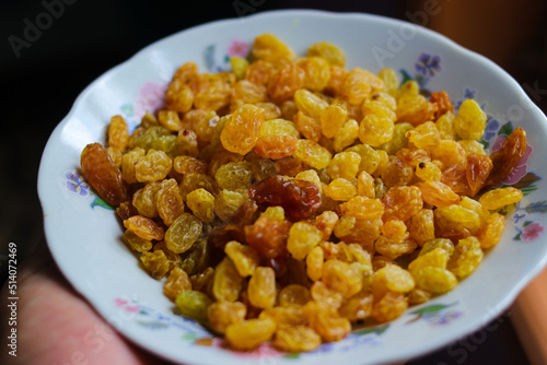 Hand holding a white plate with full of yellow raisins