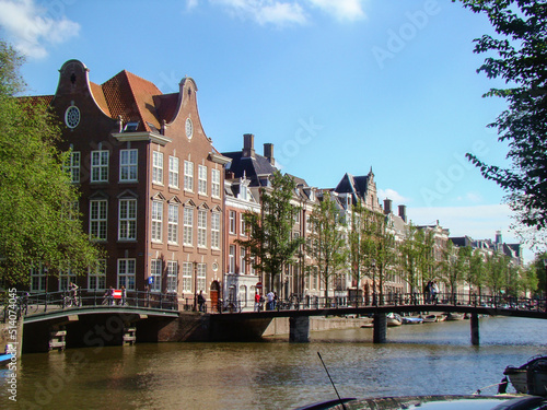 Canal in Amsterdan (Netherlands) a bridge and people in which we can see the arquitecture of amsterdam's house. photo