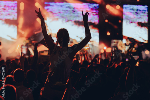 Fototapeta Silhouette of a woman with raised hands on a concert