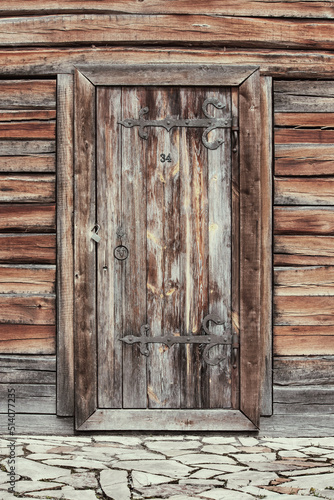 Old ancient wooden door with old wooden planks logs bark wall