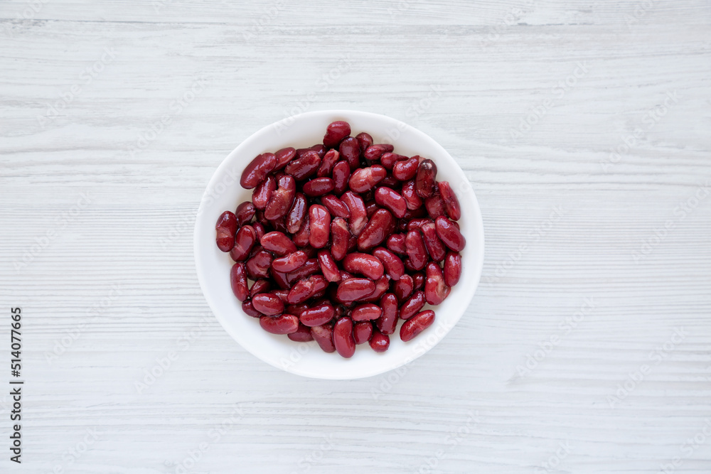 Red Organic Kidney Beans in a White Bowl on a white wooden surface, top view. Flat lay, overhead, from above. Red Organic Kidney Beans in a White Bowl on a white wooden surface, top view. Flat lay, overhead, from above.