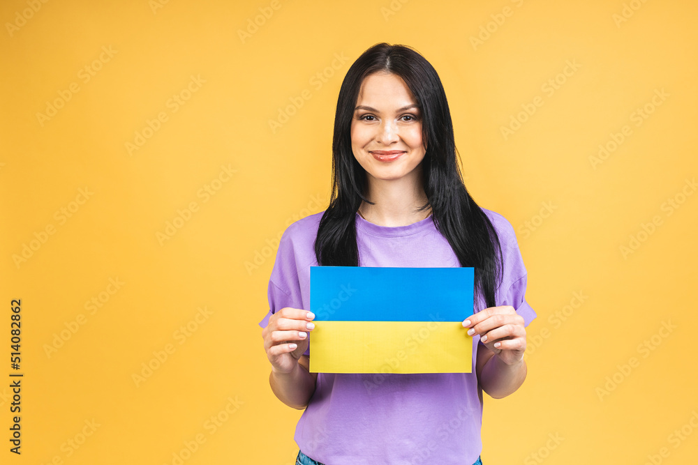Portrait of nice beautiful lovely glad cheerful woman holding in hands Ukrainian flag having fun isolated over yellow pastel color background. Portrait of nice beautiful lovely glad cheerful woman holding in hands Ukrainian flag having fun isolated over yellow pastel color background.