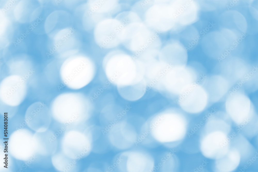 Defocused Bright abstract blue winter background with shimmering white sunspots. Bokeh. Holiday festive concept. Copy space for text. Merry Christmas and Happy New Year