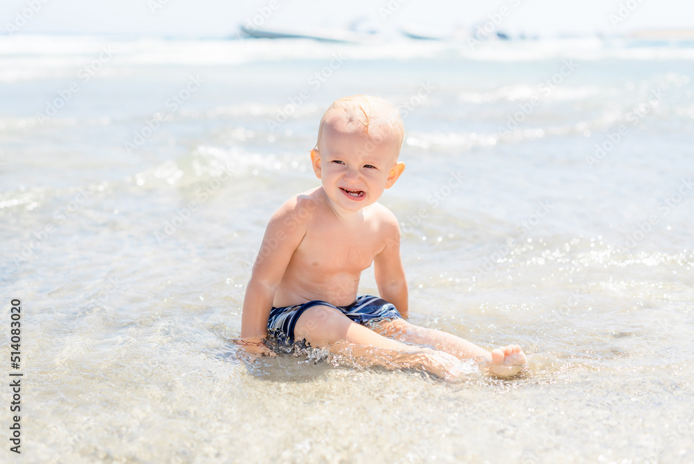 happy child boy laughing and sitting on the beach by the sea happy child boy laughing and sitting on the beach by the sea