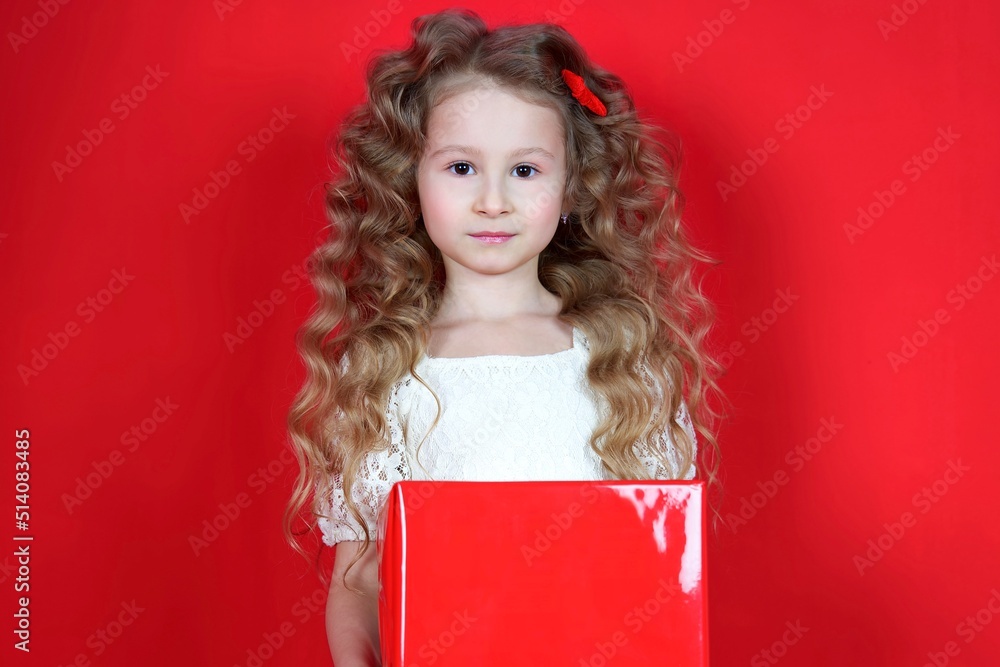 Portrait of happy positive cheerful small little kid child girl in dress isolated on red background holding red present big box, smiling, celebrating. Present, holiday, happiness concept Portrait of happy positive cheerful small little kid child girl in dress isolated on red background holding red present big box, smiling, celebrating. Present, holiday, happiness concept