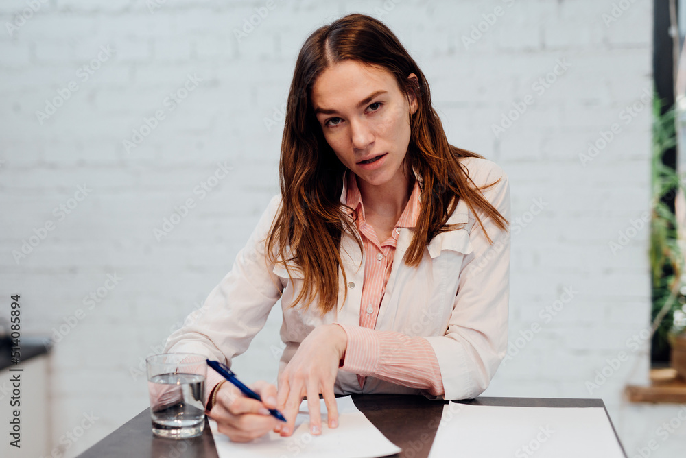 Young female doctor sits at her desk, listening intently and taking notes - obrazy, fototapety, plakaty 