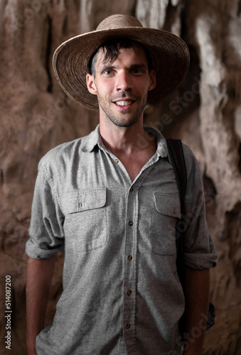 Portrait of a smiling young explorer man with blue eyes wearing a hat and a grey shirt in a cave © Miguel Serrano