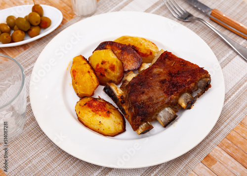 Pork ribs with boiled potatoes and spices on a ceramic plate