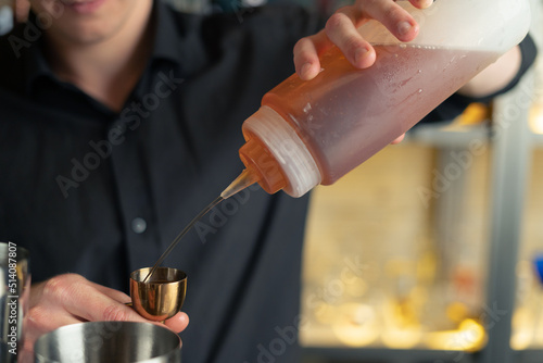 bartender prepares a cocktail in a bar  club. pours alcohol and syrups. uses ice and breaks ice