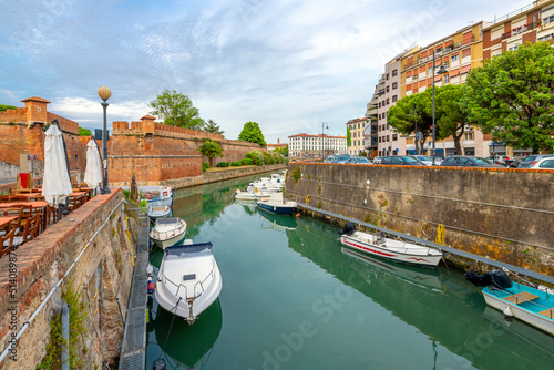 Boats line the crowded canals next to the New Fortress and an outdoor waterfront cafe at the seafront Tuscan city of Livorno, Italy.