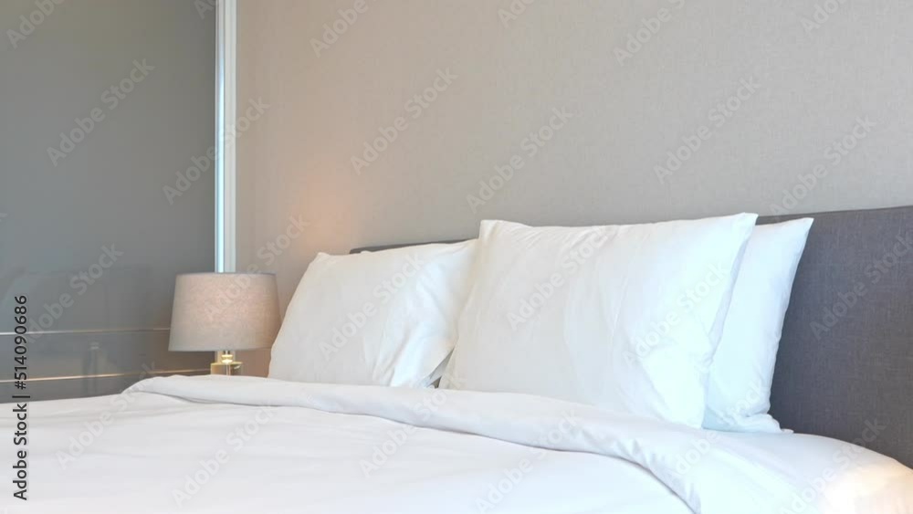 made-up king size bed with white striped linen cover and pillows at night with turned on Lamps in a hotel made-up king size bed with white striped linen cover and pillows at night with turned on Lamps in a hotel