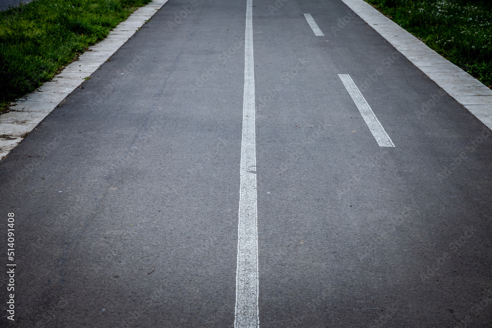 Selective blur on white road markings indicating the presence of a bicycle lane, made of black asphalt, designed for bikers, bikes and bicycles to drive safely in an urban environment...