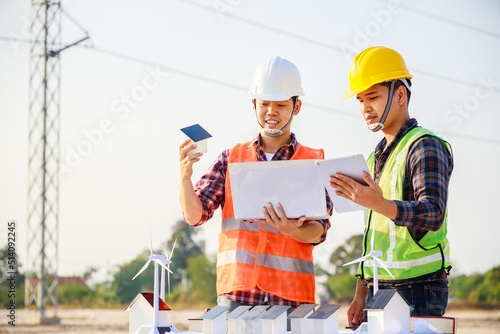 Teamwork, Leadership concept. Two Asian engineers discussing for wind turbine and solar cell project