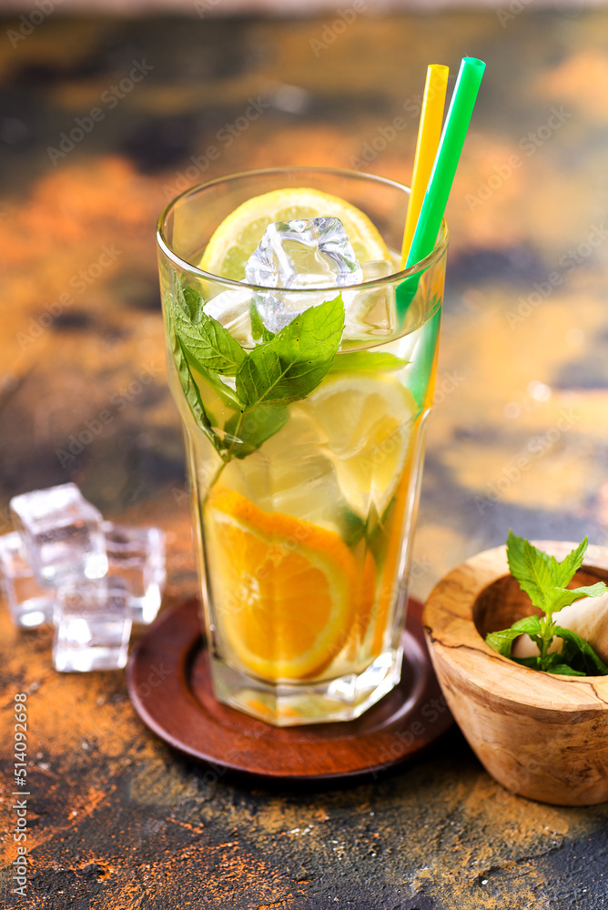 Fototapeta premium Homemade lemonade in a glass, lime, lemons and mint on a wooden board.
