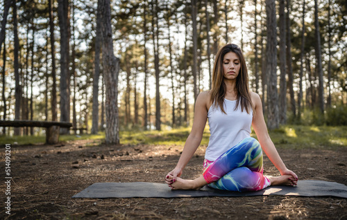One caucasian woman practice yoga in the nature in woods or park sitting alone healthy lifestyle meditation and modern relaxation antistress concept copy space front view