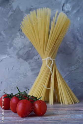 a bunch of tomatoes on the background of a bunch of spaghetti tied with a rope.