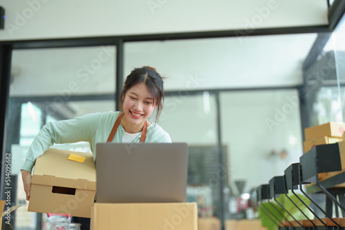 A portrait of a small startup, an SME owner, an Asian female entrepreneur checking orders to arrange the produce before packing the products in the inner boxes with the customers. Freelance concepts © Jirapong