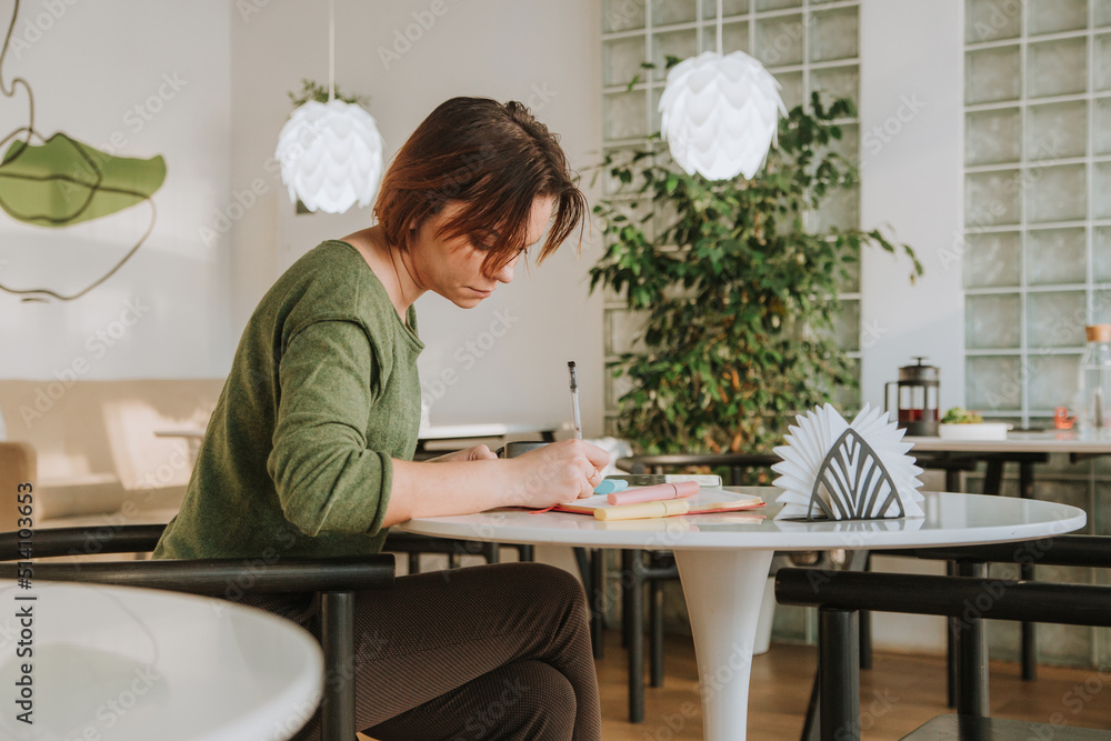 a young woman is sitting at a table in a cafe a young woman is sitting at a table in a cafe