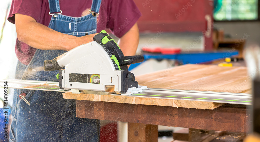 Closeup Carpenter man using electric saw cutting wood in carpentry workshop,