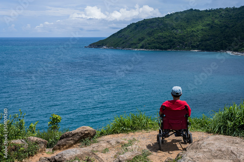 Disabled woman sitting in wheelchair looking at the sea , Handicapped travelling concept