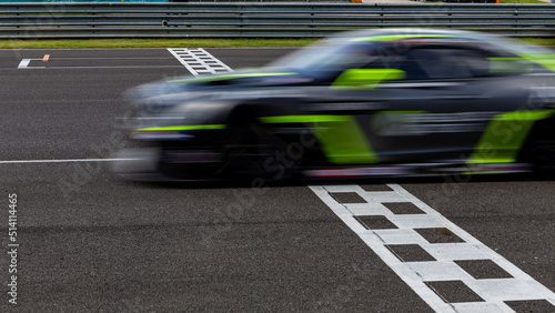 Race car blurred motion crossing the finish line on international circuit speed track, Motion blur Racing car crossing finish line on asphalt main straight racetrack. photo
