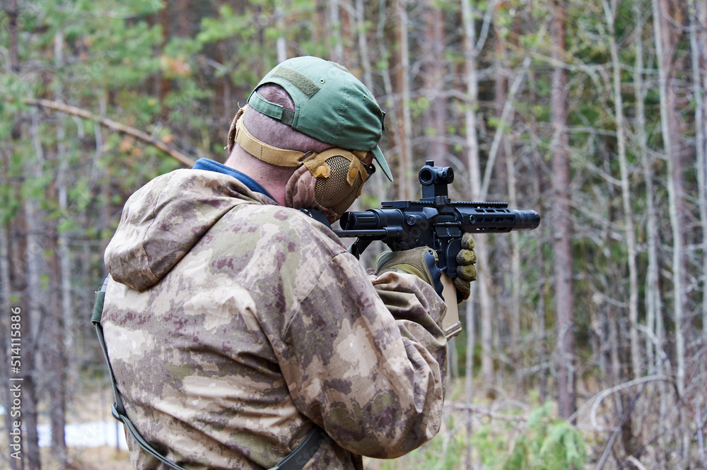 Fototapeta premium a man in camouflage shoots from a machine gun in the forest